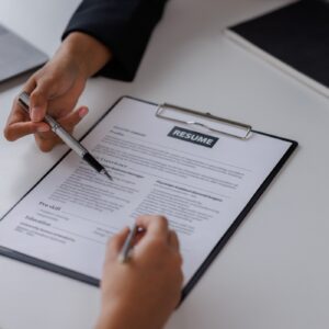 Hands reviewing a resume on clipboard.