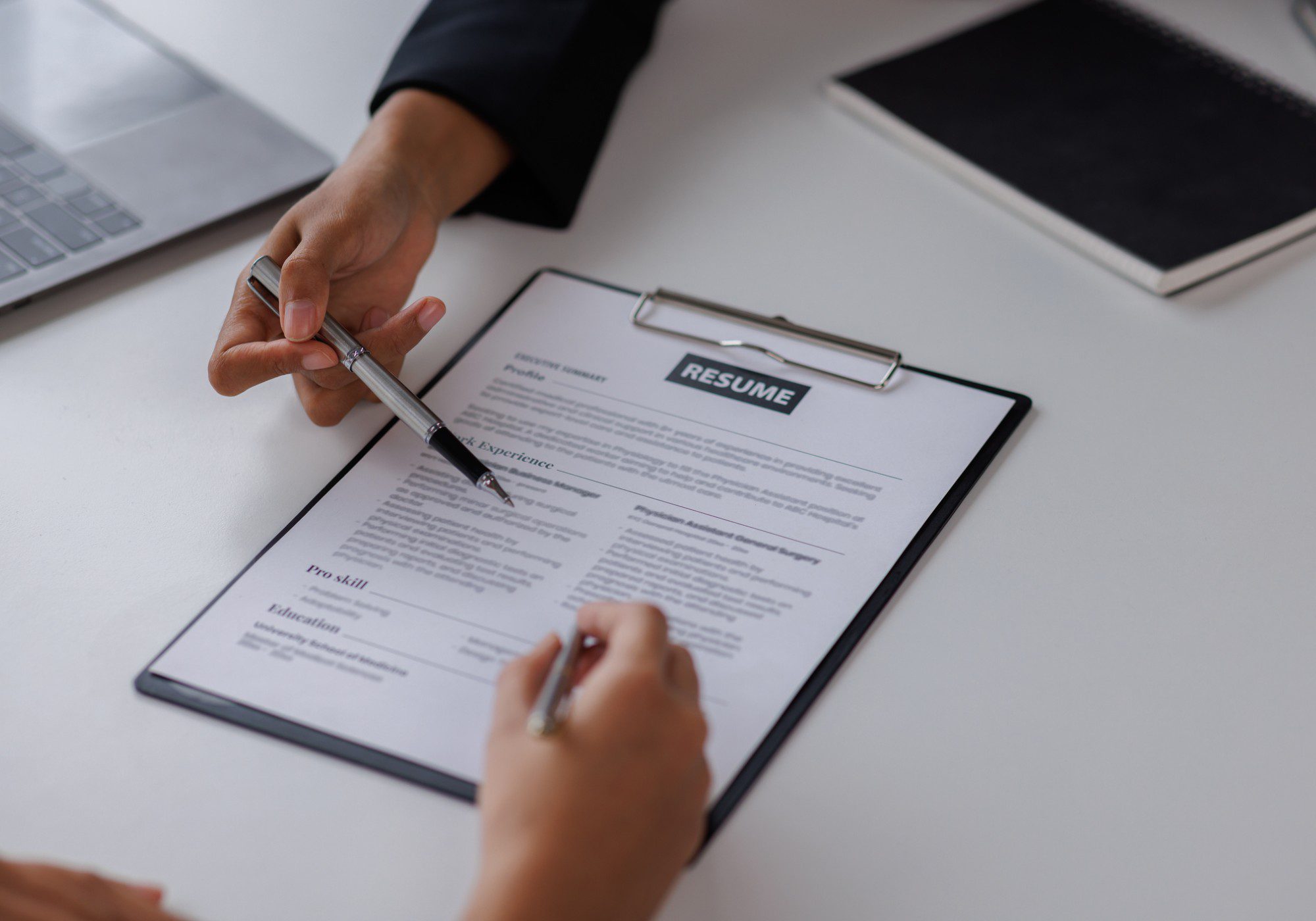 Hands reviewing a resume on clipboard.